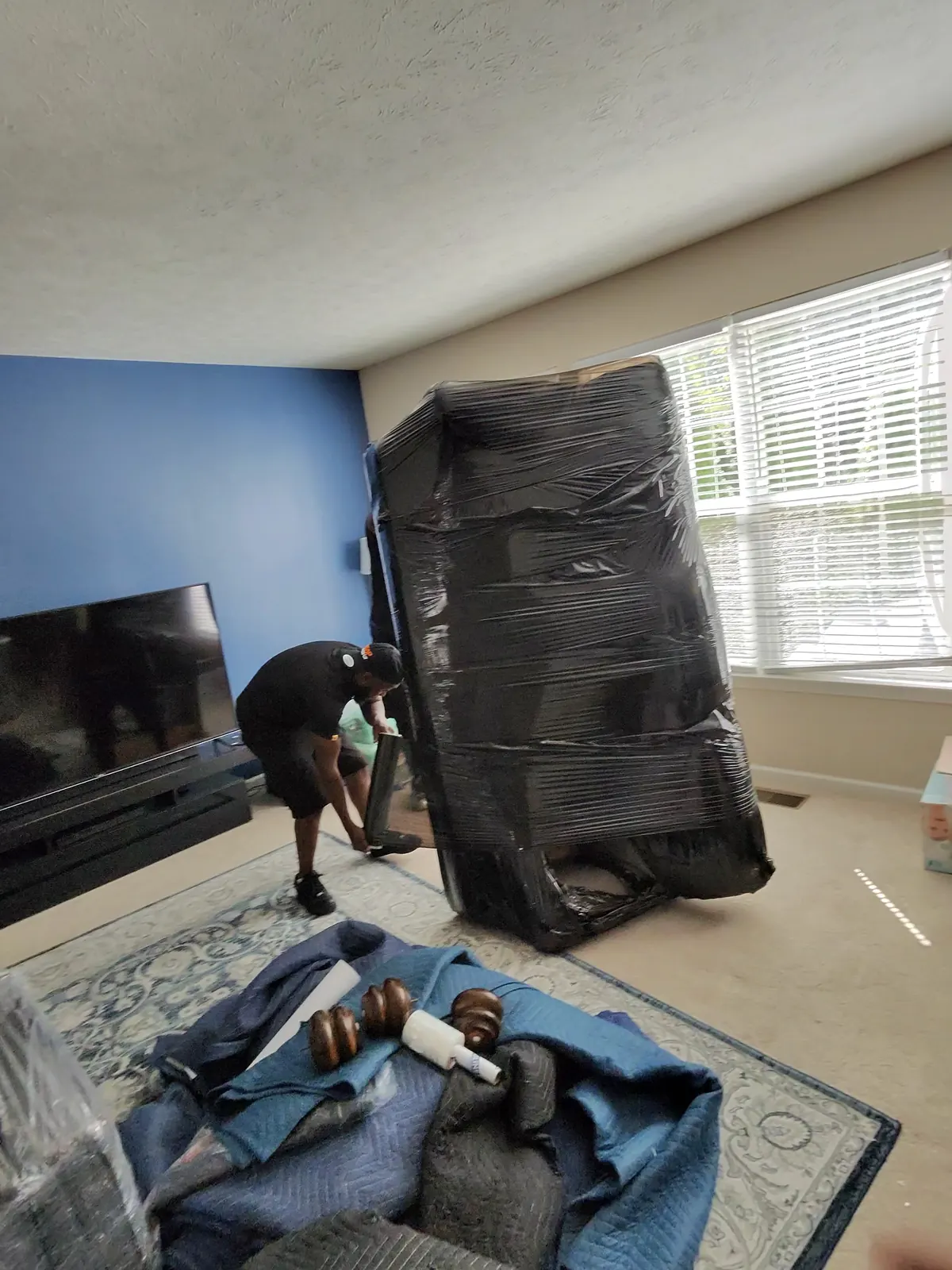 ASAP Moving crew member beside an upright wrapped furniture piece and moving blankets in Avon Lake.