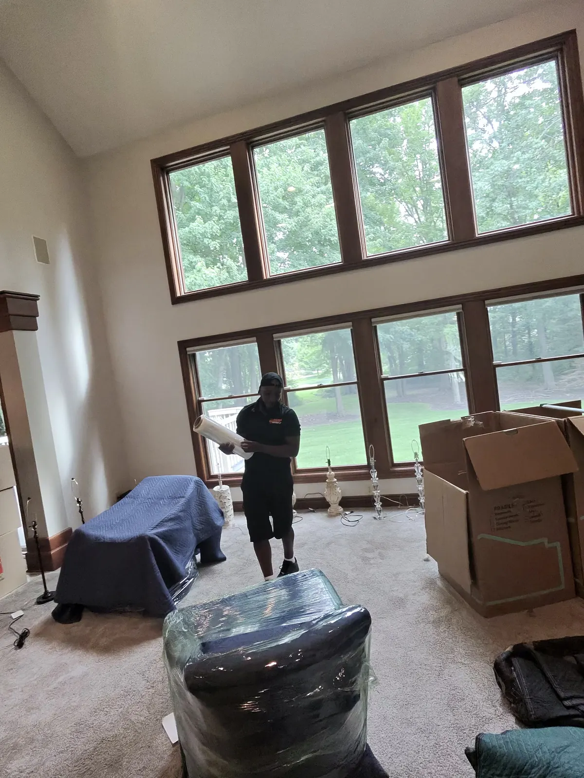 ASAP Moving crew member in an Avon room with wrapped furniture and packed boxes.