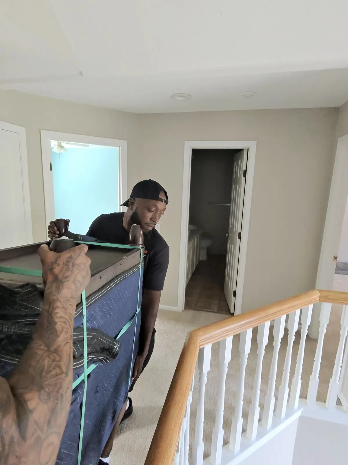 ASAP Moving crew members handling wrapped furniture beside an indoor stair railing in Solon, Ohio.